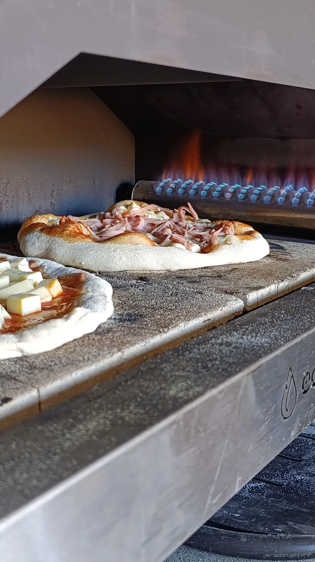 Pizzas a la piedra saliendo del horno a la llama